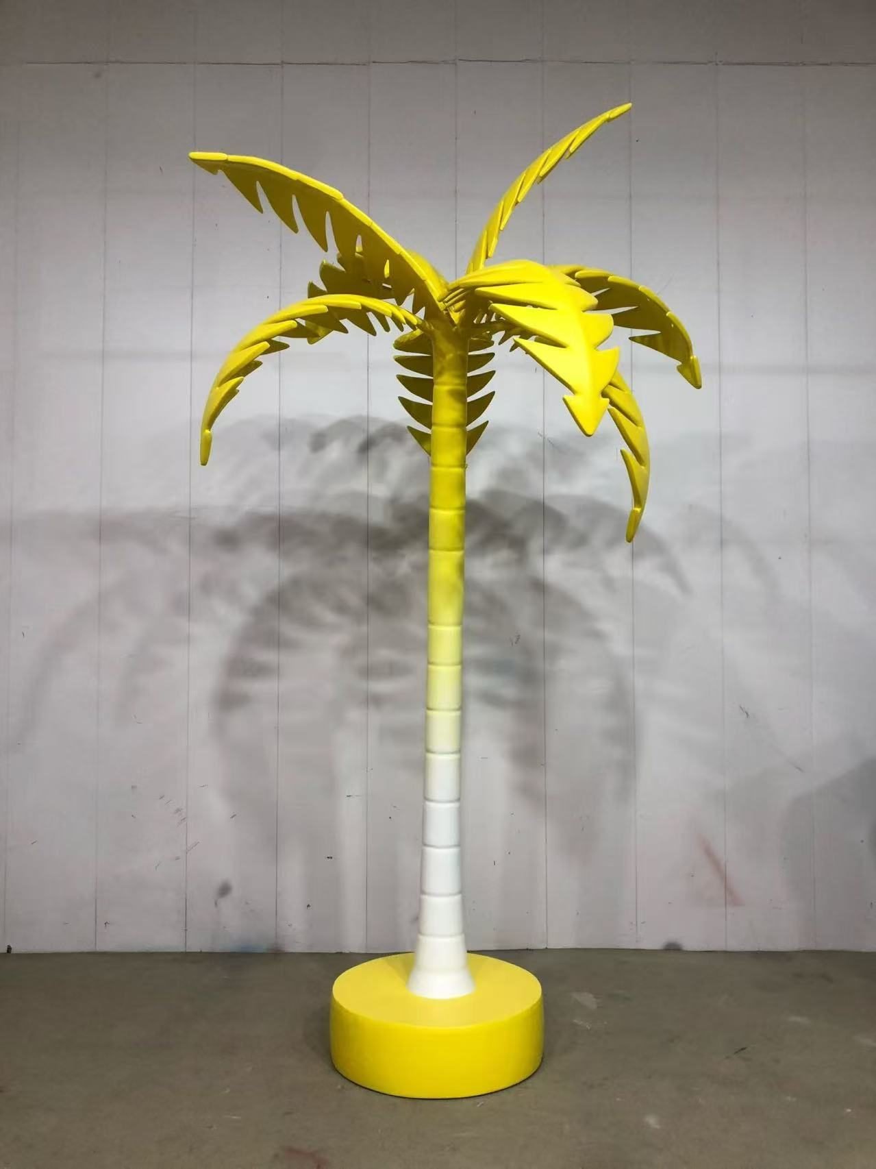 Yellow artificial palm tree display prop on a round base