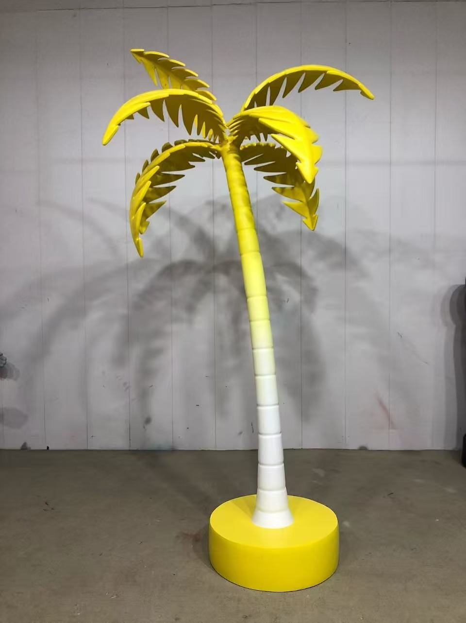 Artificial palm tree with yellow leaves and a pale trunk