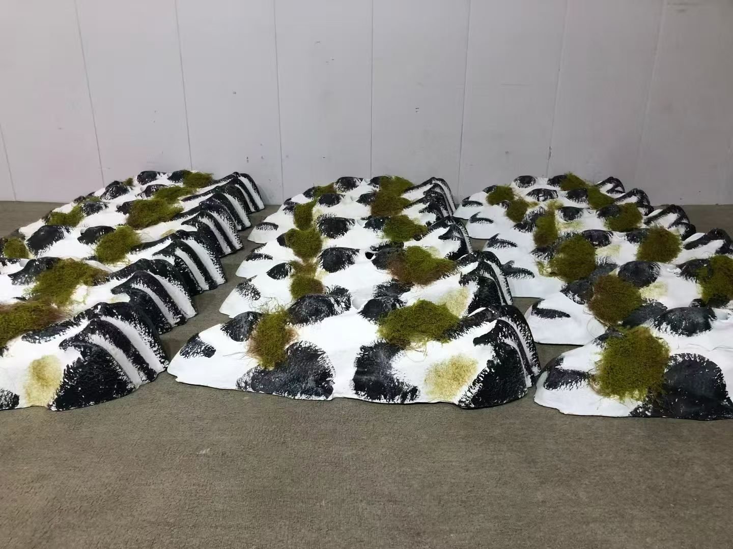 Black and white faux rock display props with green moss details