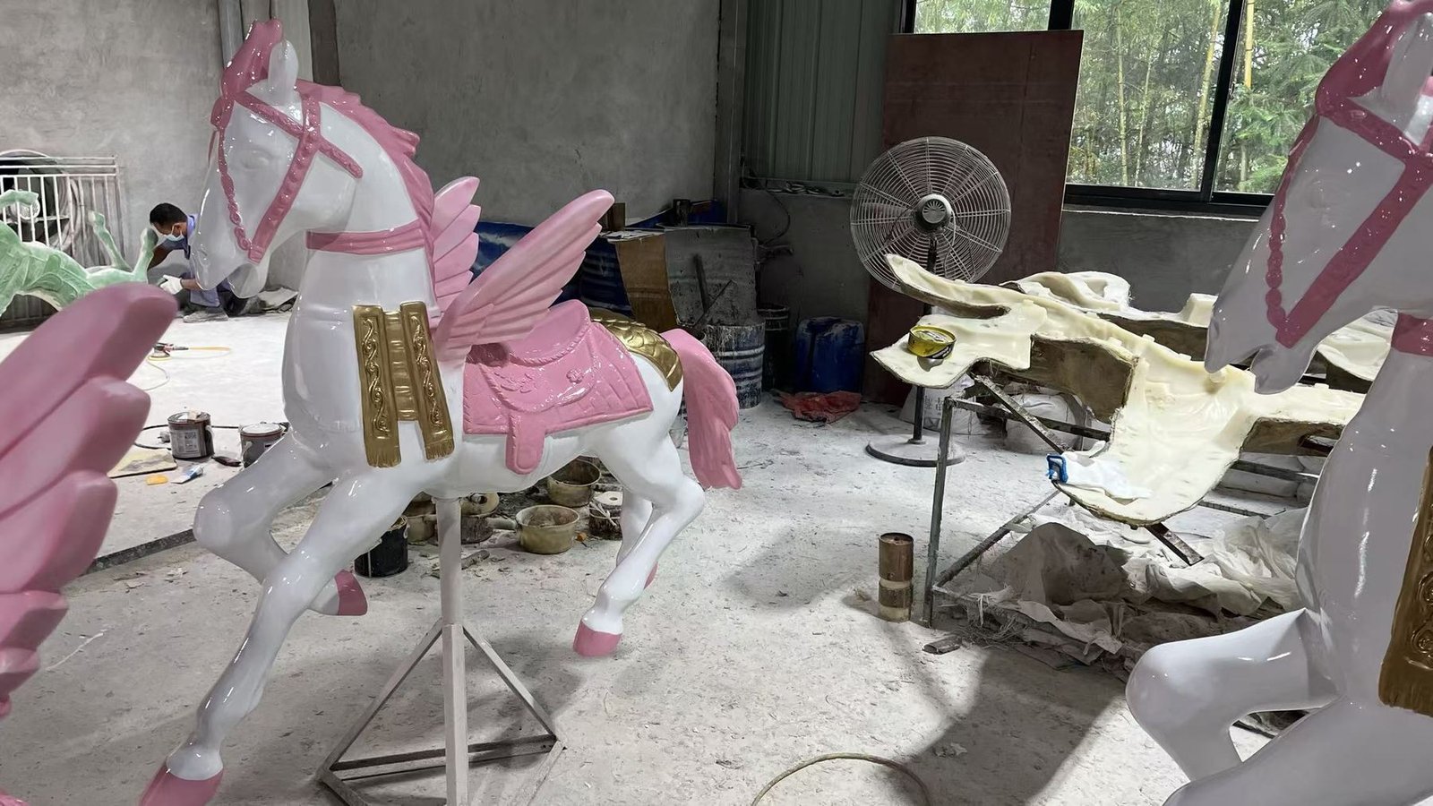 White and pink winged horse display sculpture in a workshop
