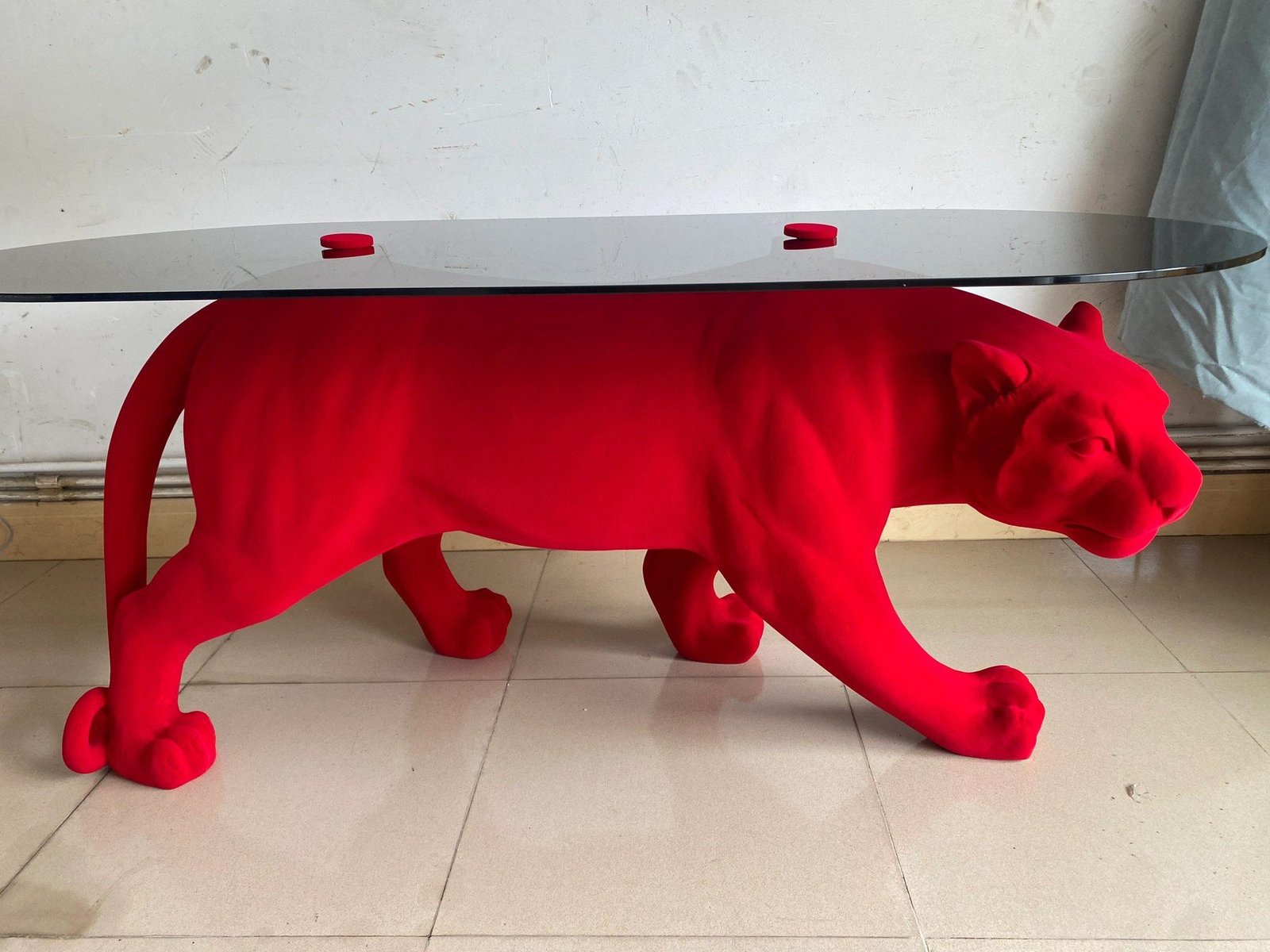 Red flocked panther display table with a dark oval top