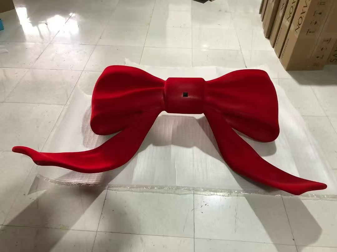 Oversized red bow display prop with sweeping ribbon tails