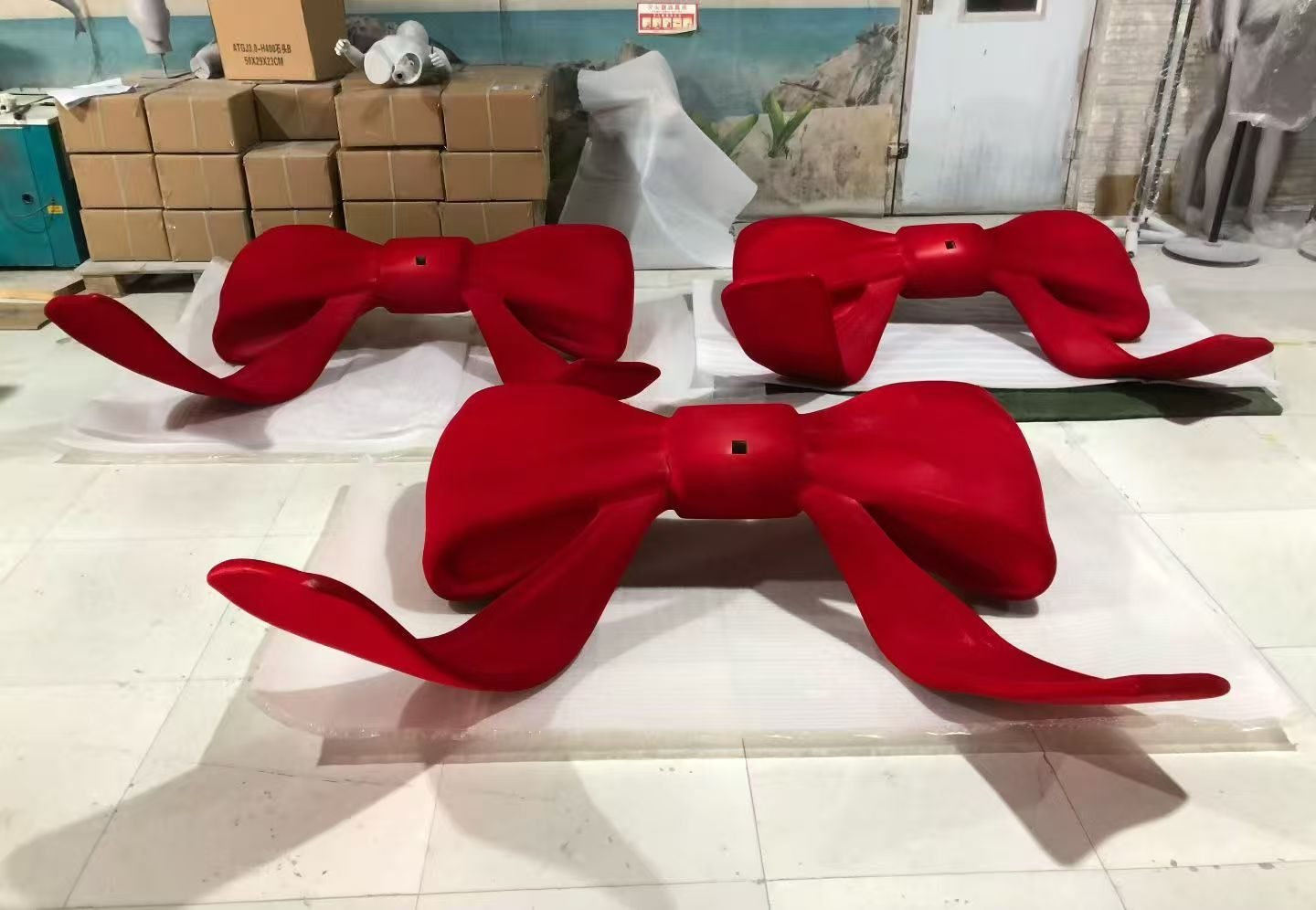 Three red bow display props arranged on a workshop floor