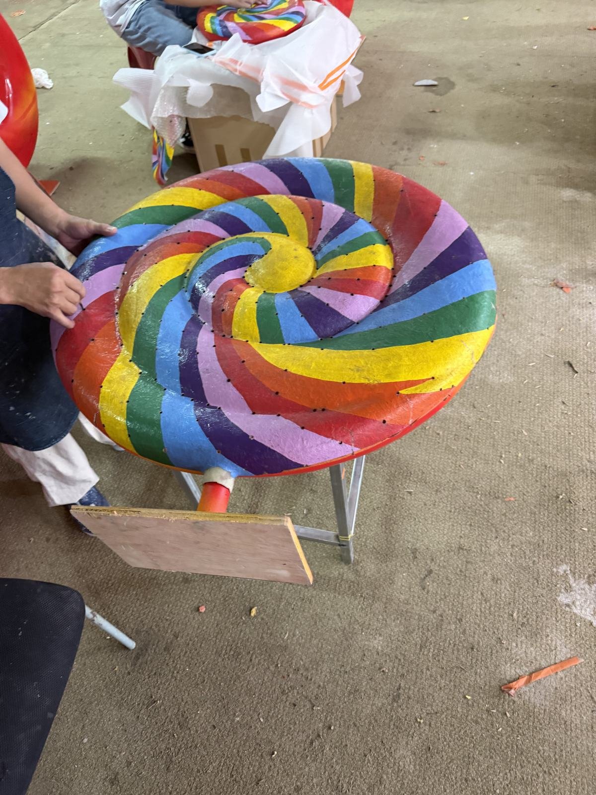 Hand-finishing the colored surface of a rainbow lollipop display prop