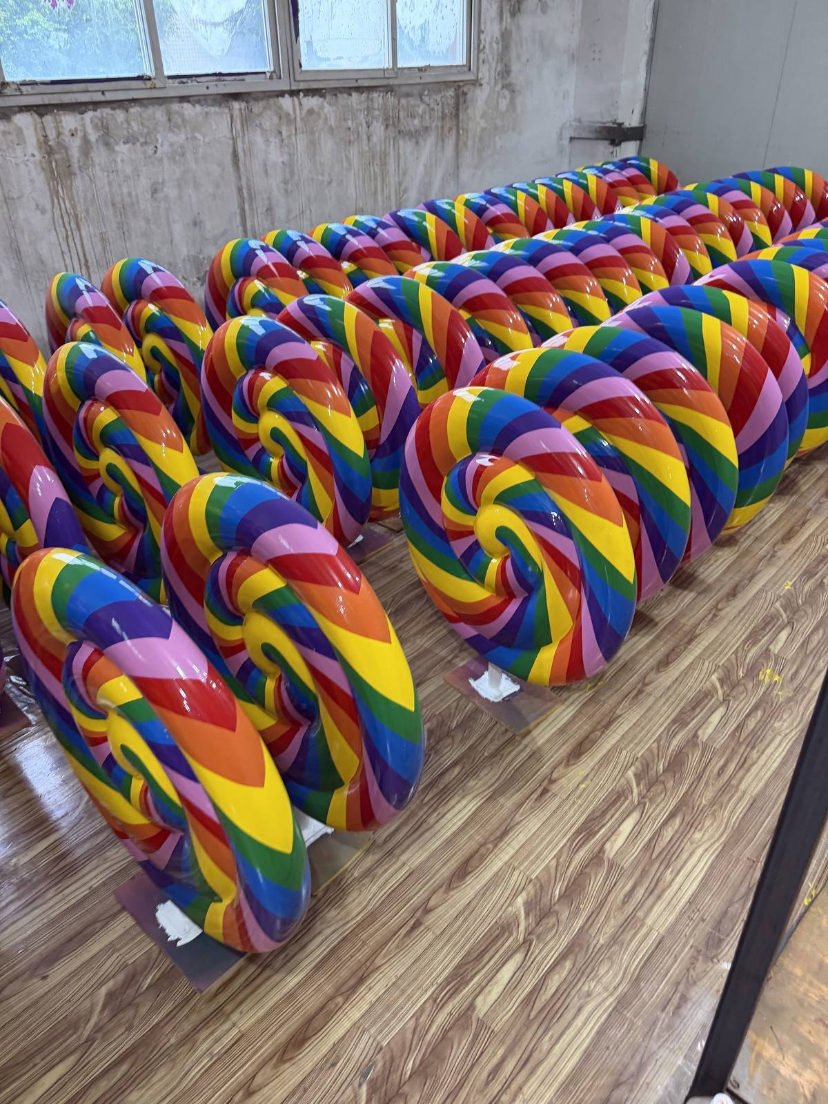 Batch of finished rainbow spiral lollipop display props arranged in the workshop.