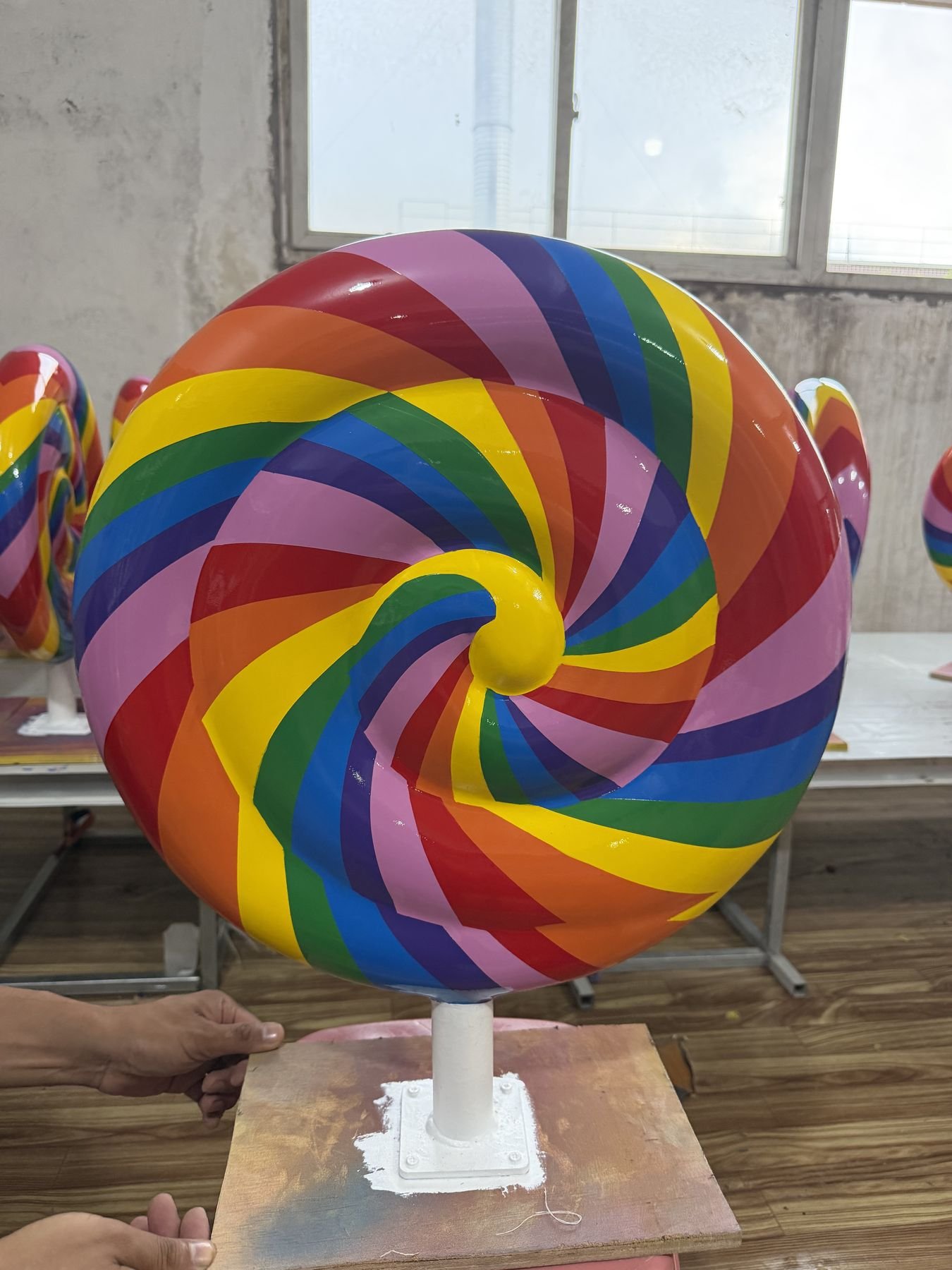 Alternate face of a finished rainbow spiral lollipop prop on its workshop support.
