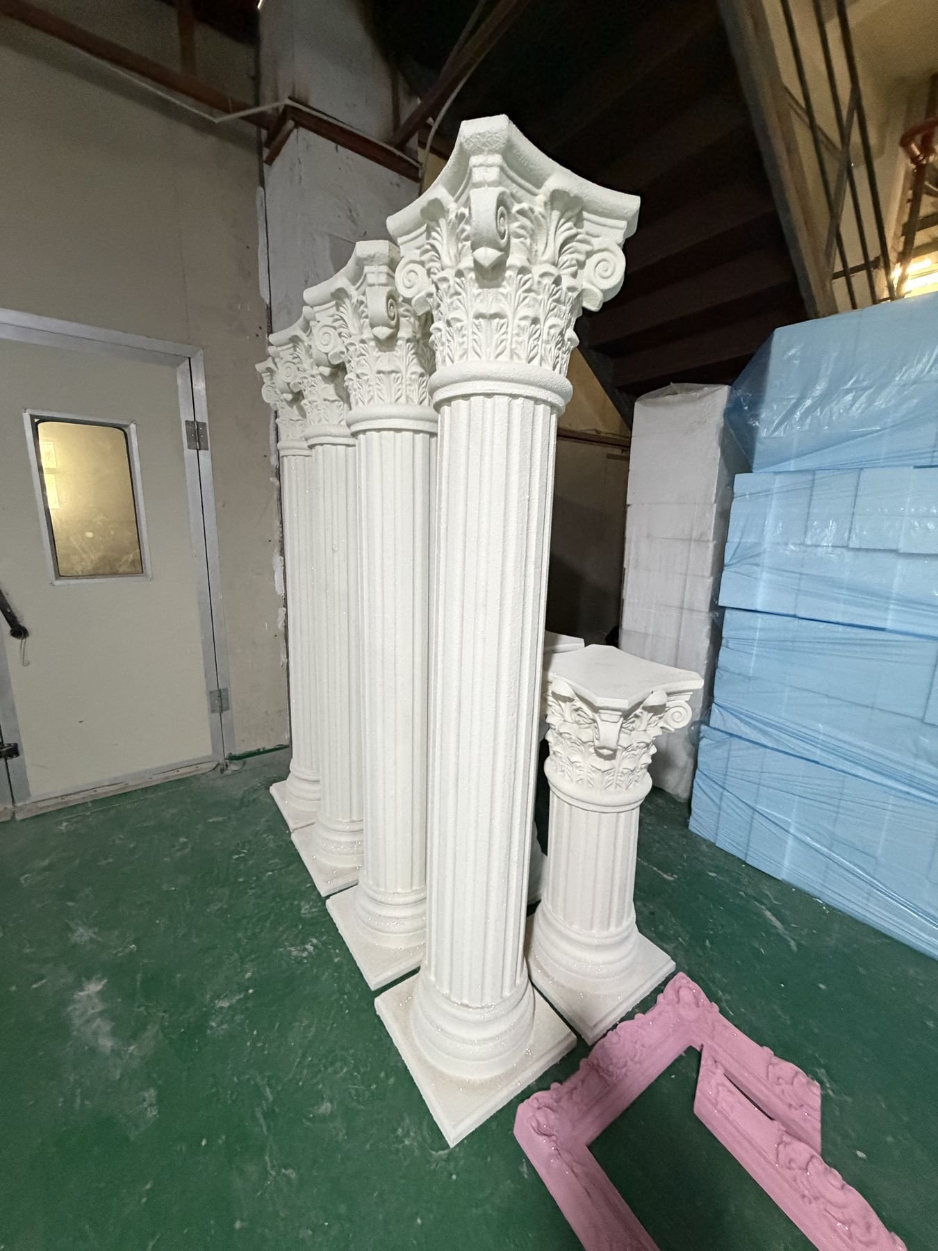 Tall and short white Roman column display props in a workshop