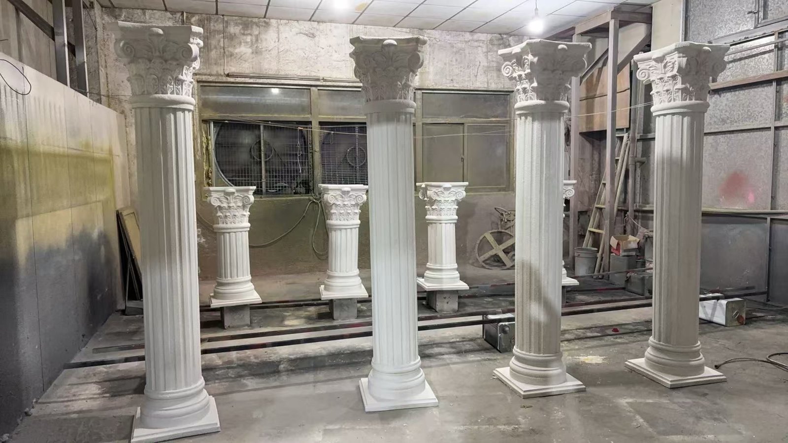 Tall and short classical column display props arranged in a workshop