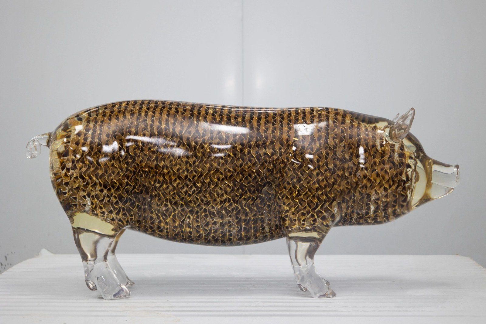 Transparent pig sculpture with clear legs and gold-tone pattern
